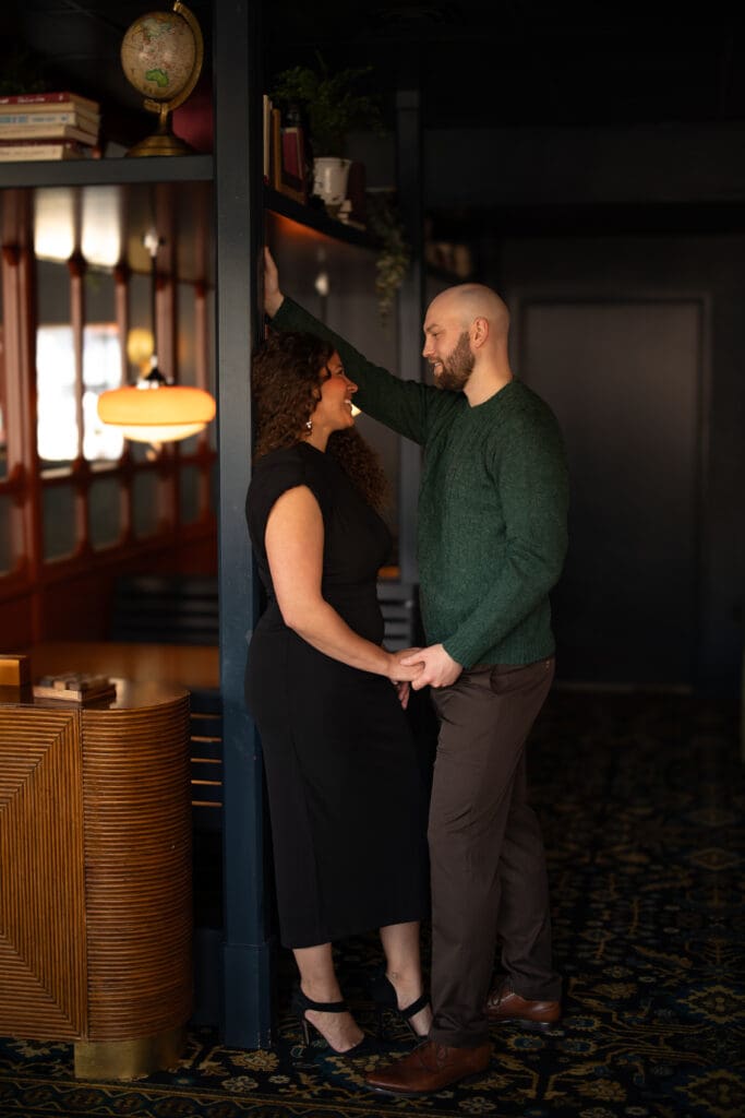 couple leaning against a post holding hands