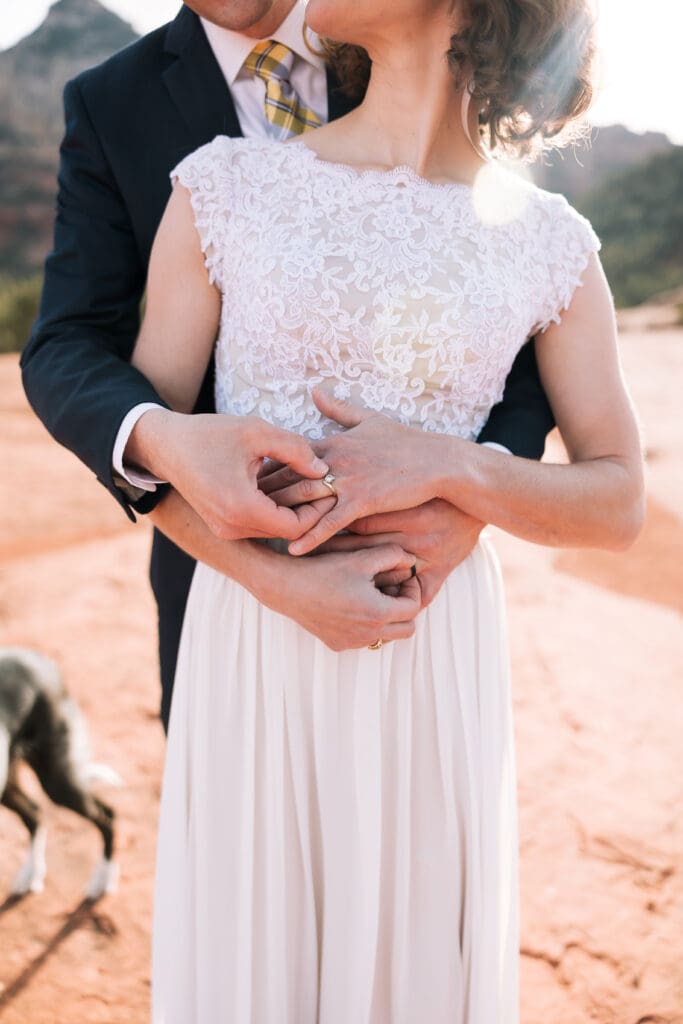 A groom places a ring on his brides finger.