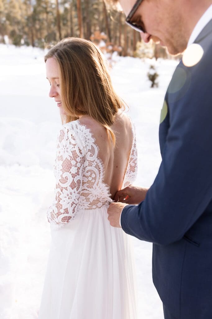 The groom helps zip the bride into her dress.