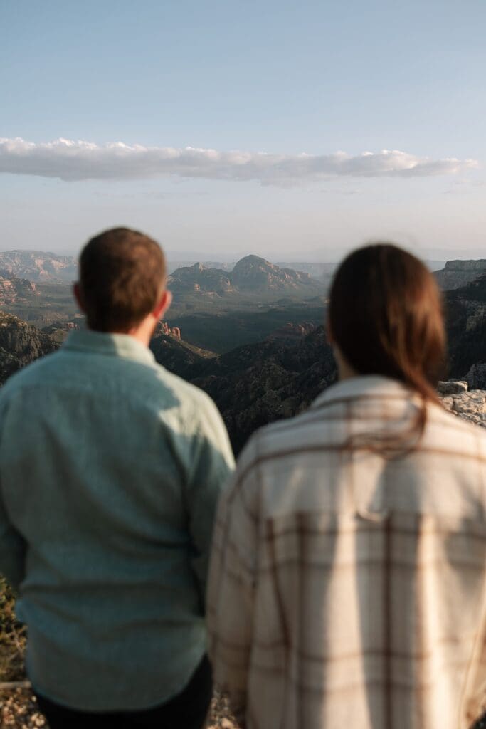 A couple stands side by side overlooking Capitol Butte aka Thunder Mountain in the distance. 