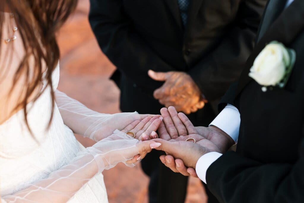 Bride and groom holding wedding rings in their hands before the exchange during a Secret Slickrock Sedona elopement