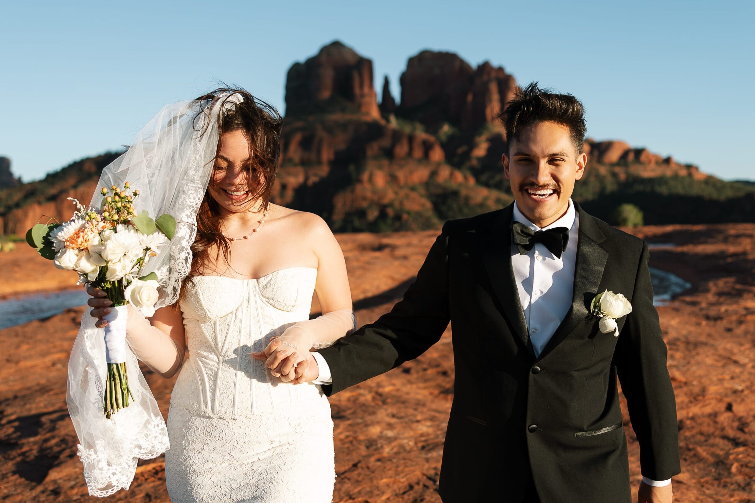 Wide-angle elopement portrait at Secret Slickrock Sedona with sunset views of Cathedral Rock in October.