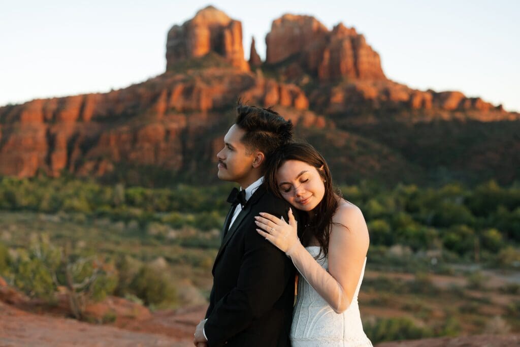 a bride and groom have a quiet moment while the sun sets on cathedral rock. 