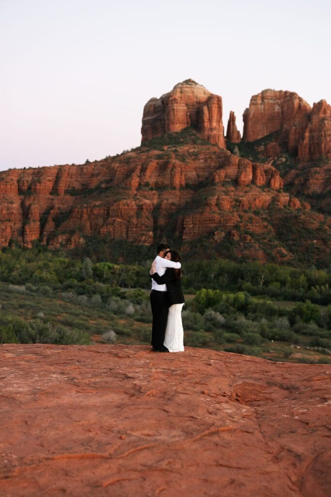 A bride and groom share a quiet moment together as the sun sets behind the sedona red rocks. 