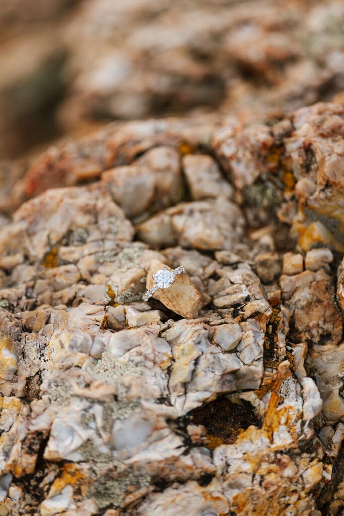 A wedding band and engagement ring placed on a rock.