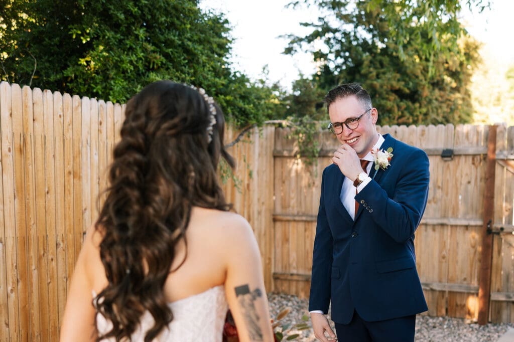 Groom with glasses smiling happily at his bride during their first look outside in Sedona.