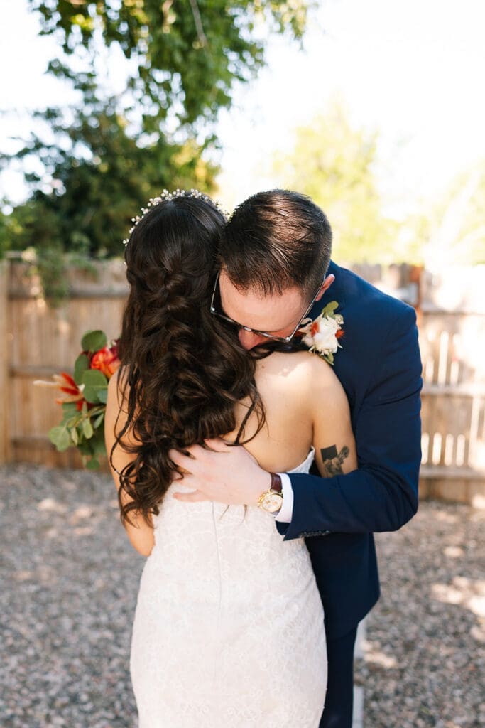 Bride and groom embracing tightly and laughing together during a private first look before heading out to the trail.