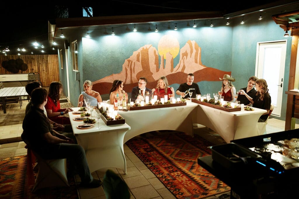 Candlelit outdoor dinner table setup at an AirBnB with guests seated and celebrating an intimate Sedona elopement reception.