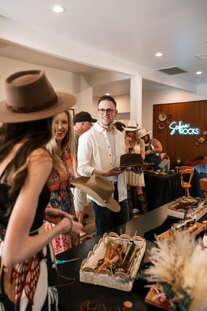Candid photo of family and friends at a mobile hat bar by Sage and Stone during a casual pre-wedding gathering.