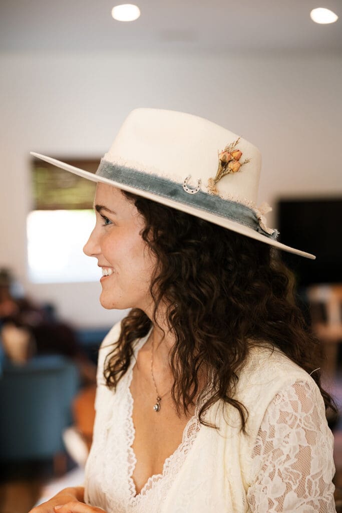 Beautiful candid portrait profile of the bride smiling, wearing her customized white cowboy hat at a mobile hat bar before her Sedona elopement.