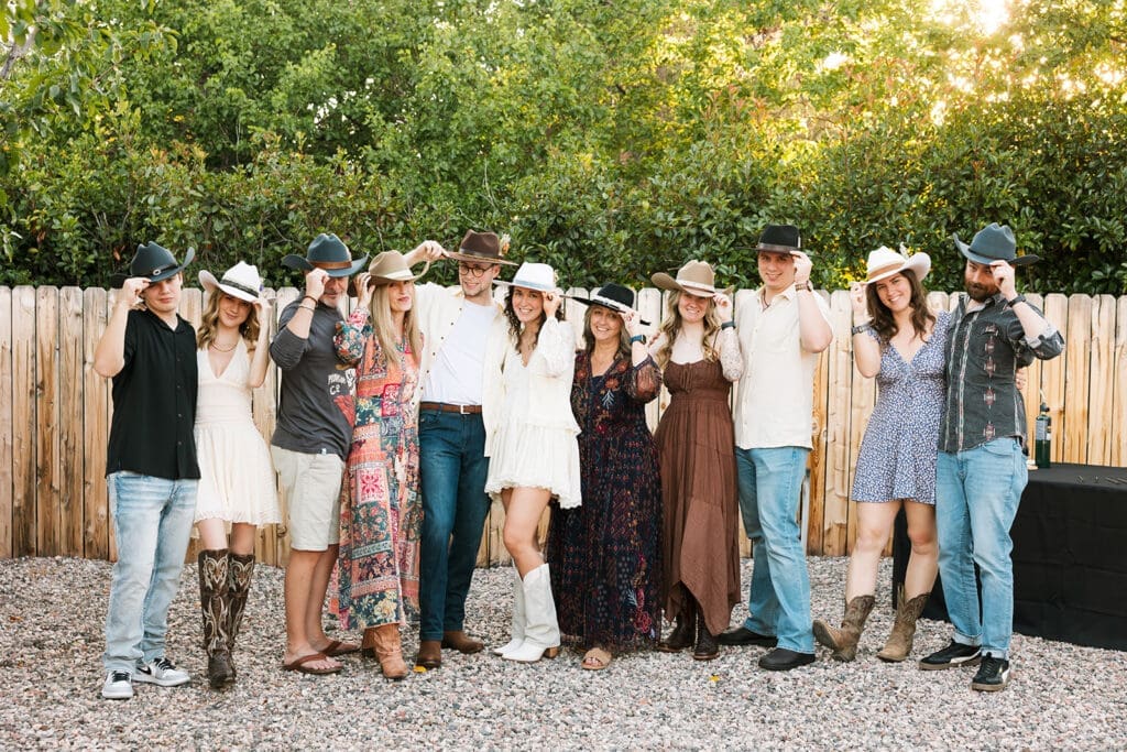 Wide group photo of the group members posing outside and wearing their custom hats with Sedona scenery in the background.