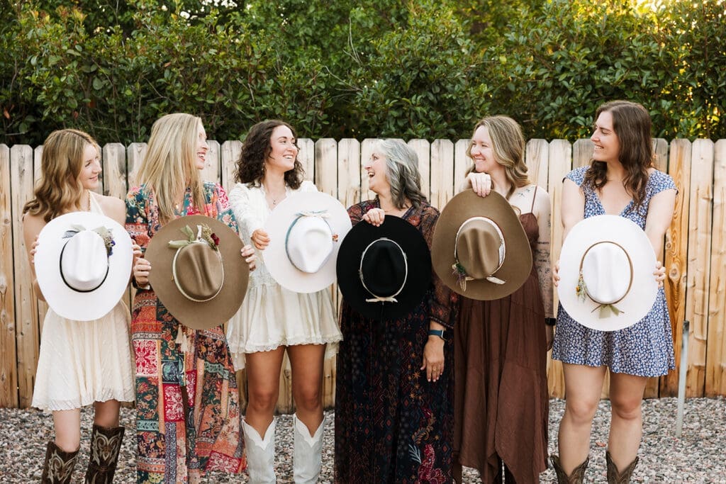 Bridesmaids wearing their custom cowboy hats and floral dresses posing together outside before an off-roading Sedona elopement.