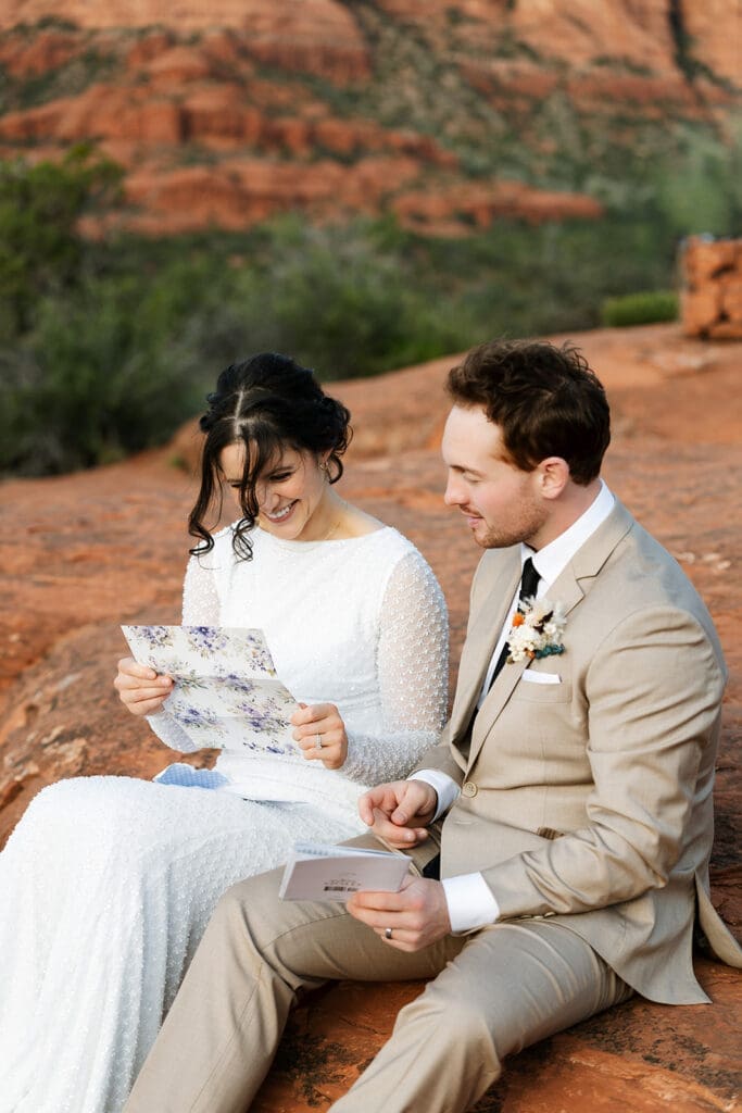 Close-up portrait of the bride and groom smiling together while reading handwritten cards during their Sedona elopement.