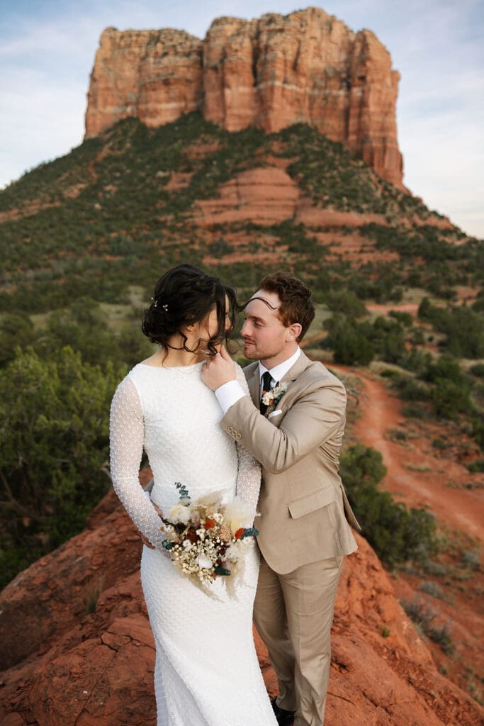 Bride leaning gently against the groom with towering Bell Rock scenic views in the background.