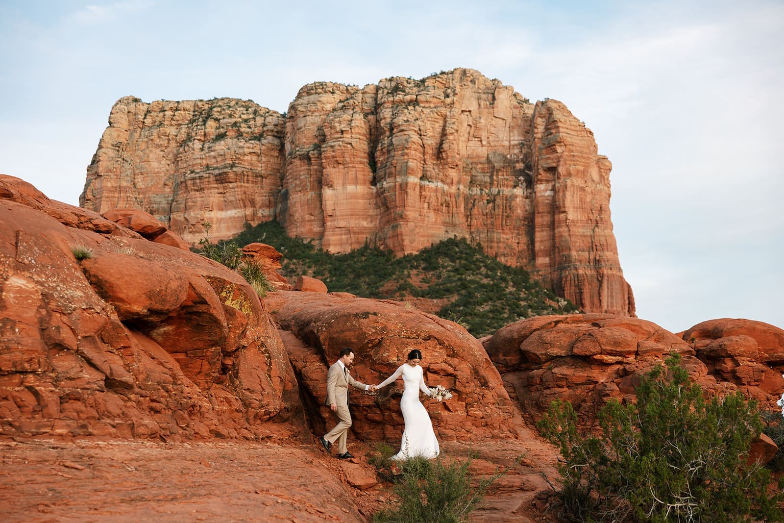 A bride and groom standing together on red rocks at Baby Bell Rock during a Sedona sunset elopement.