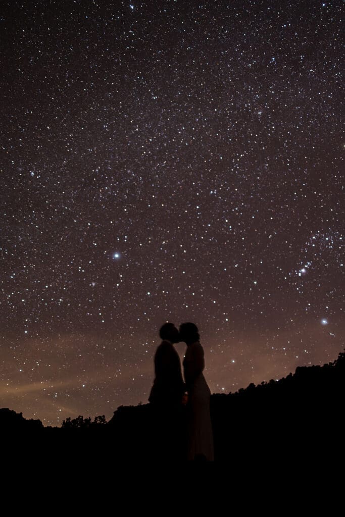 Silhouetted long-exposure photo of the bride and groom kissing under a brilliant, star-filled night sky during their Sedona elopement.