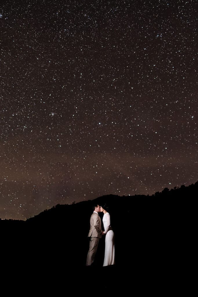 Silhouetted long-exposure photo of a bride and groom kissing under a starry night sky during their Sedona sunset elopement.